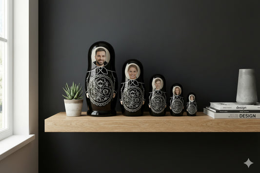 Set of black nesting dolls with white designs on a wooden shelf against a dark wall.